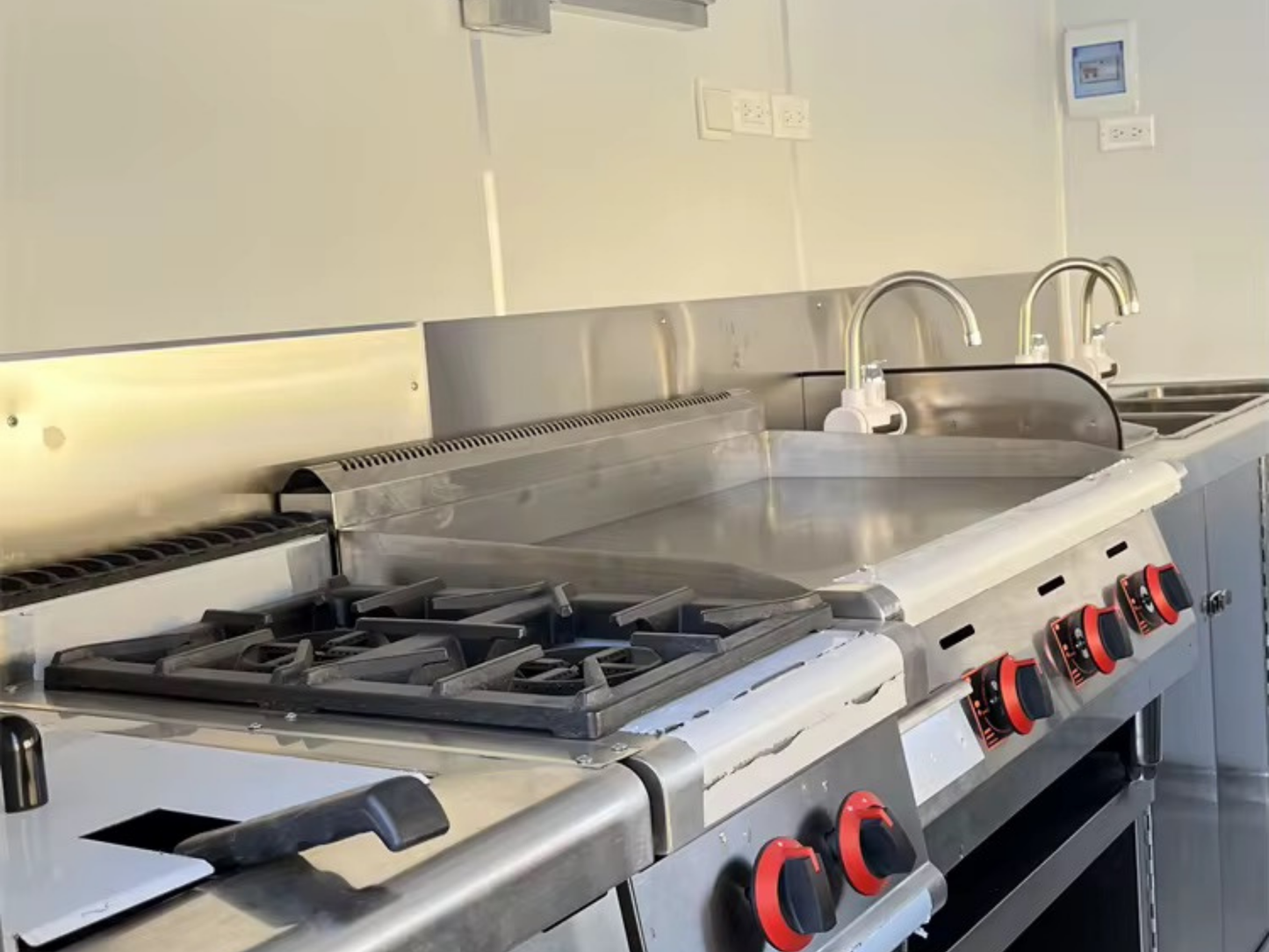 Commercial kitchen stove with multiple burners and control knobs in a professional setting.