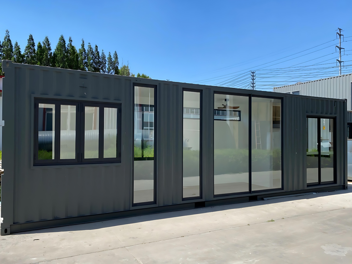 Modular building made from shipping containers with large windows on a clear day.