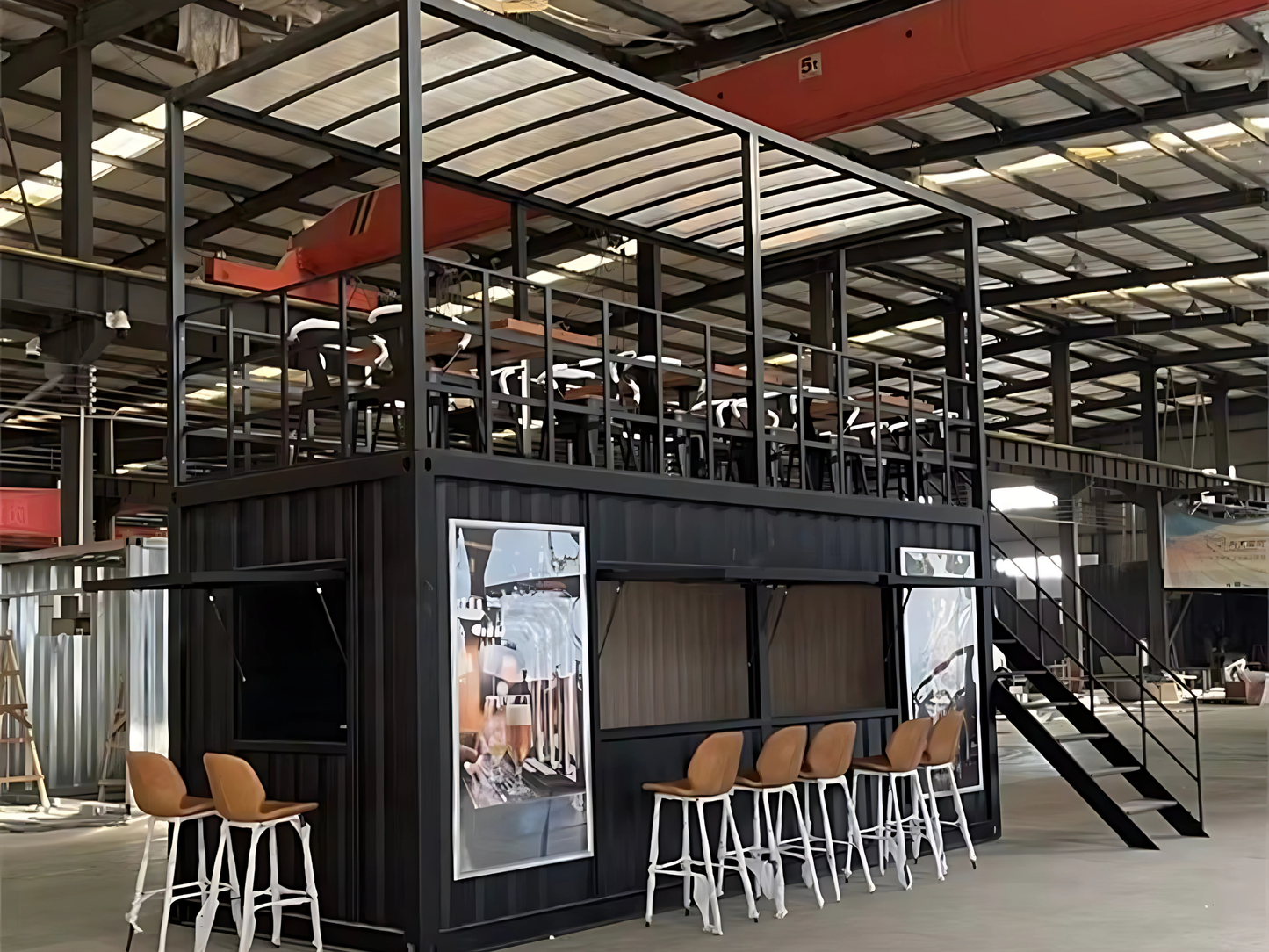 Modern industrial interior with black container structure, stools, and a staircase.
