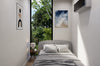 Modern bedroom with gray bedding, nightstands, and wall art.