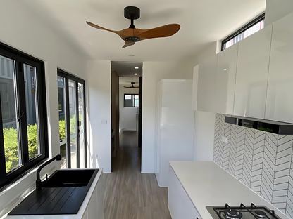 Modern kitchen interior with white cabinets, black countertop, and wooden ceiling fan.