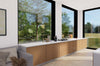 Modern kitchen with wooden cabinets and large windows overlooking a garden.