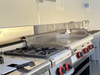 Commercial kitchen stove with multiple burners and control knobs in a professional setting.