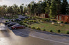 Modern container residential complex with cars parked on a street and greenery.