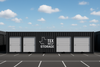 Storage containers with 'TEX SELF STORAGE' branding under a blue sky with clouds.
