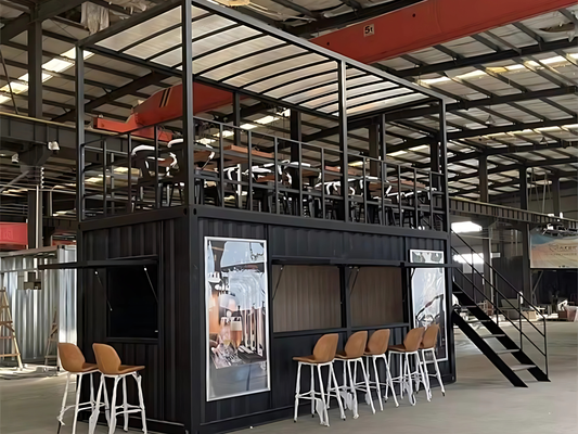 Modern industrial interior with black container structure, stools, and a staircase.