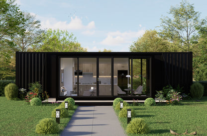 Modern black container house with large glass windows in a green, tree-lined setting.